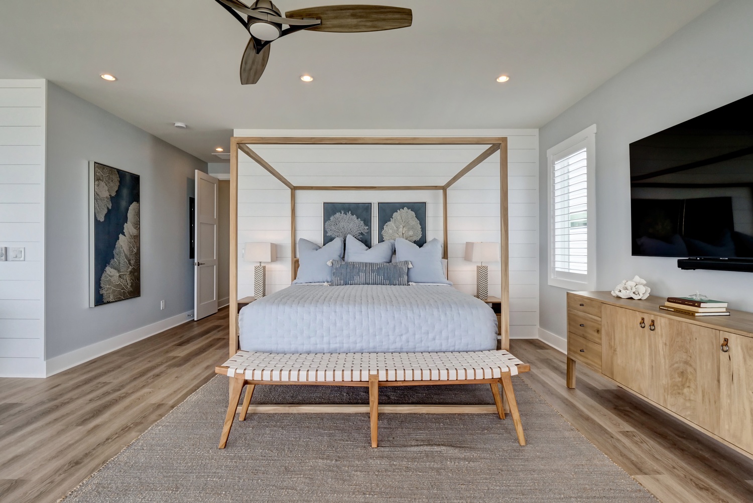 Light wood canopy bed with blue and white bedding in the Beach House primary bedroom