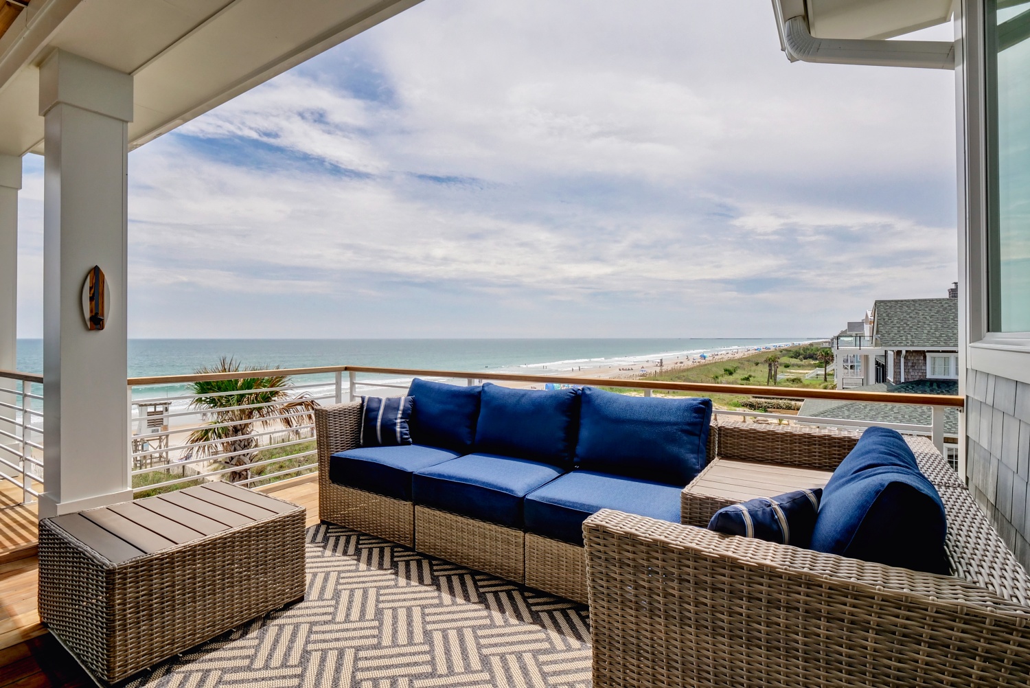 Woven outdoor sectional with deep blue cushions overlooking the beach