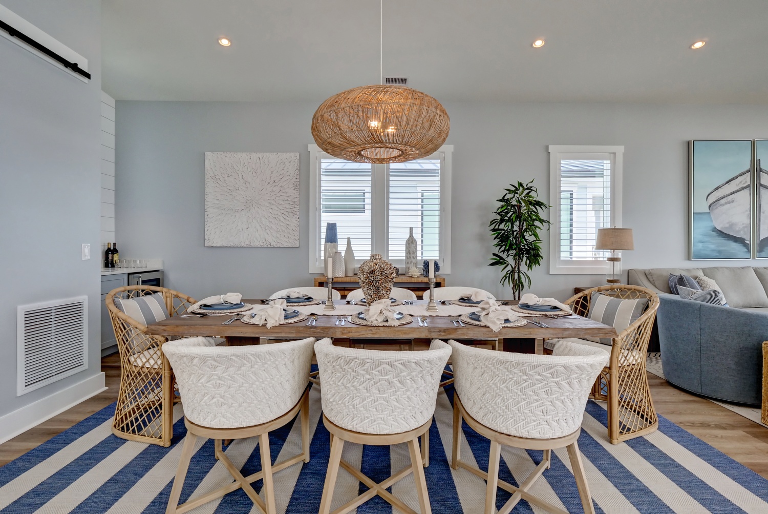 Beach House dining room with woven pendant, round table, and blue striped rug